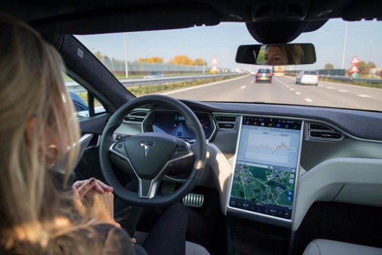 Una donna al volante di una Tesla. L'auto guida da sola.