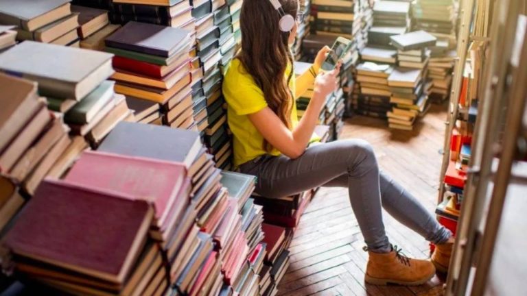 Una ragazza al cellulare circondata da libri.