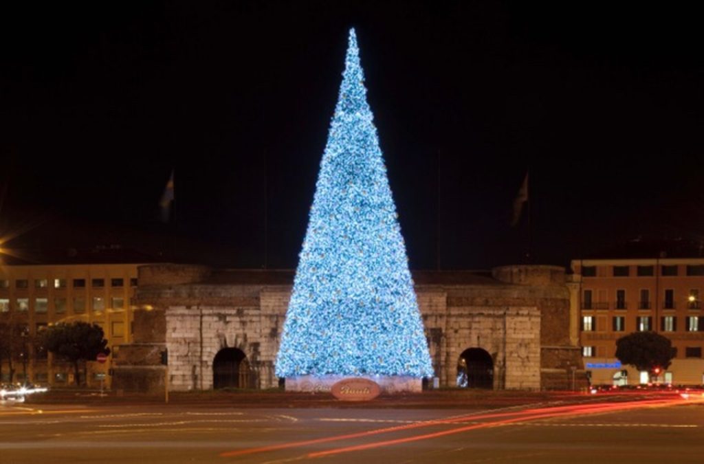 Albero di Natale Bauli illuminata di notte con lo sfondo di Porta Nuova