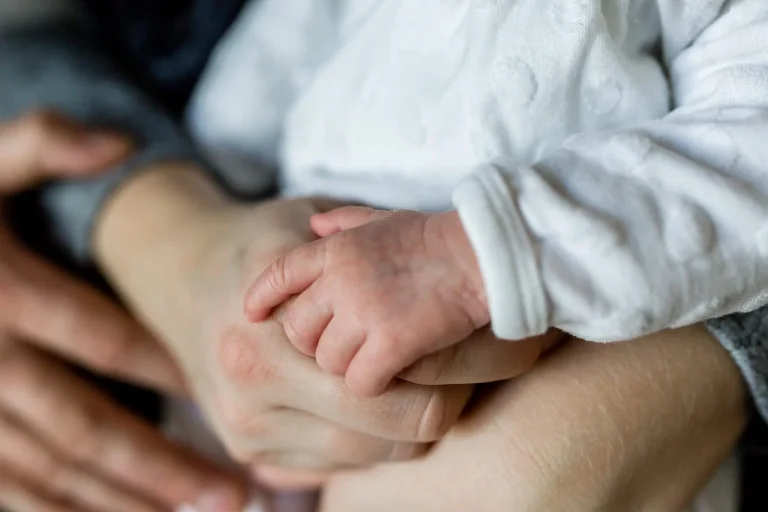 Immagine della piccola mano di un neonato in braccio alla madre